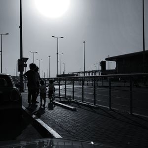 Rear view of men walking on street against sky in city