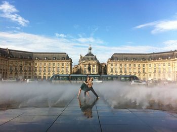 Man with sculpture in city against sky