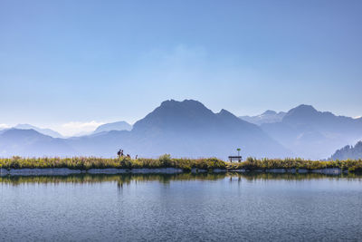 Scenic view of lake and mountains against blue sky