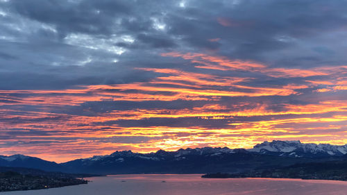 Scenic view of mountains against dramatic sky during sunset