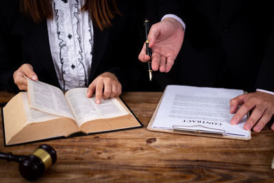Midsection of woman reading book on table
