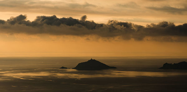 Scenic view of sea against dramatic sky during sunset