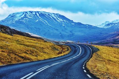 Road leading towards mountains against sky