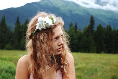 Young woman with white flowers in hair against mountain