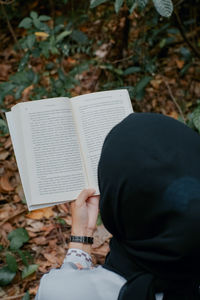 High angle view of woman reading book outdoors