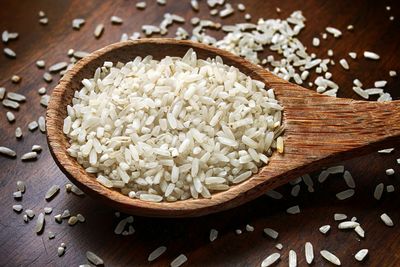 Close-up of raw rice in wooden spoon on table