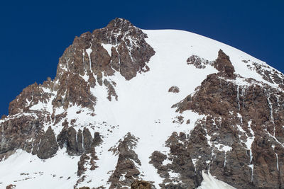 Low angle view of snowcapped mountains against clear sky