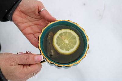 Cropped hand of person holding clock against white background