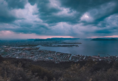 Aerial view of city by sea against sky