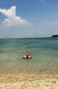 Young woman in sea against sky