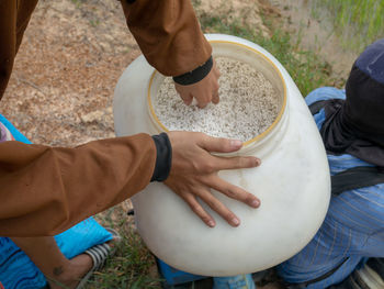 Low section of man holding container while standing by friend on rock