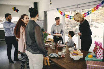 Grandfather showing birthday cake to boy while happy family enjoying at party