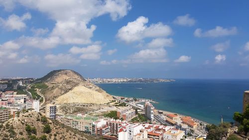 Aerial view of townscape by sea against sky