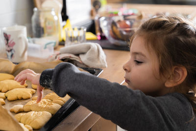 Cute girl touching cookie at home