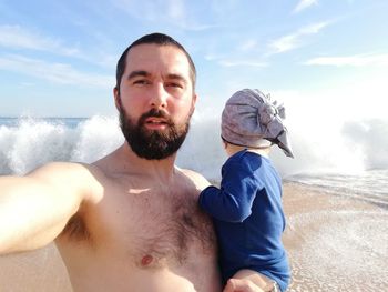 Portrait of father carrying son against ocean