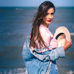 Portrait of young woman wearing sunglasses while standing at beach