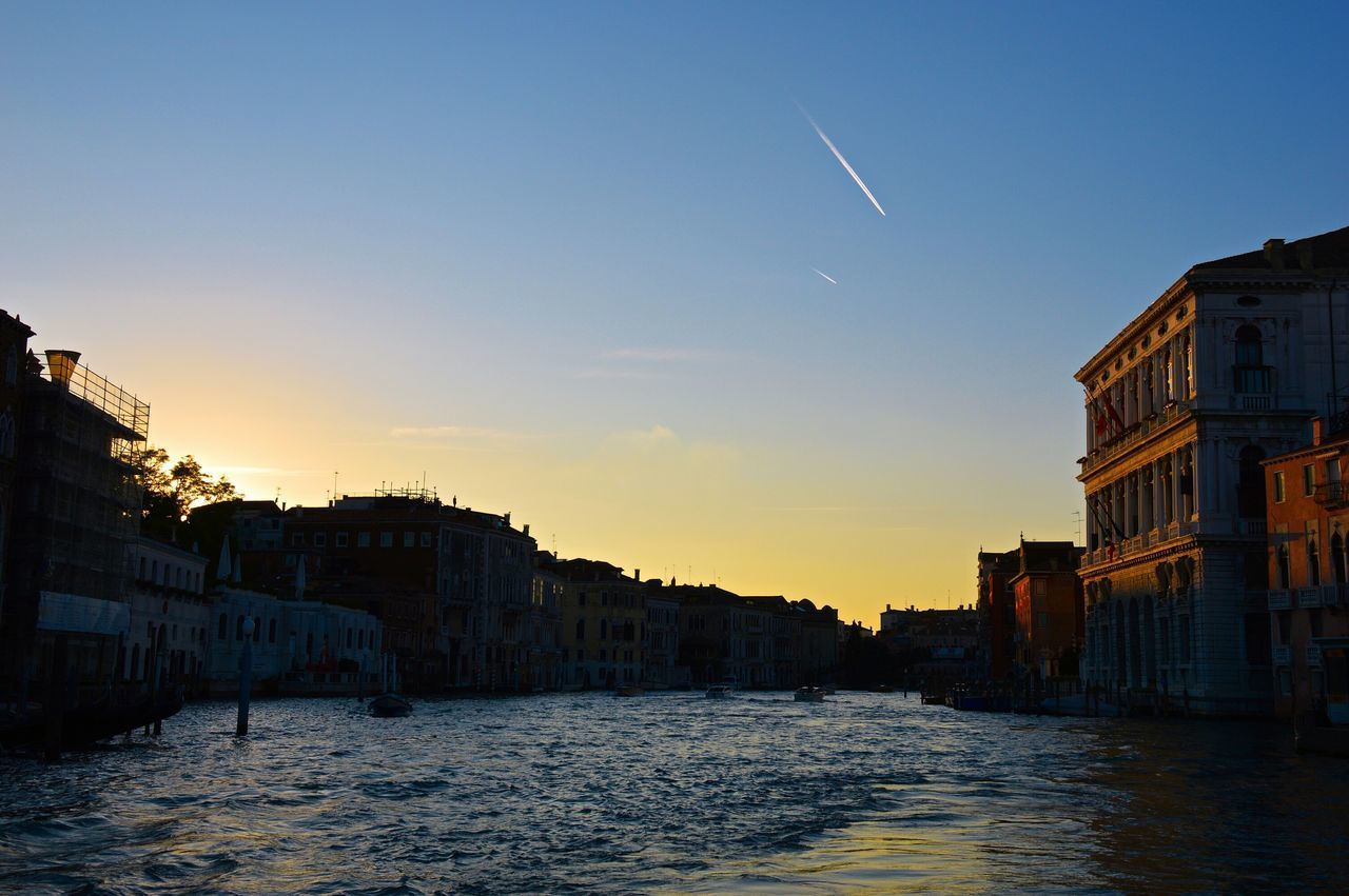 RIVER WITH BUILDINGS IN BACKGROUND AT SUNSET