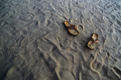 High angle view of flip-flops in sand