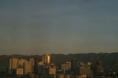 Buildings in city against sky at sunset