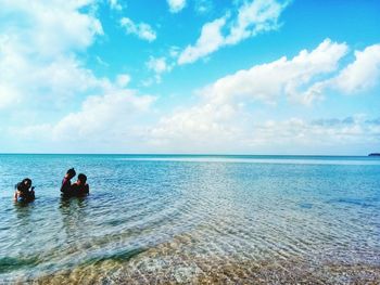 People sitting on beach against sky