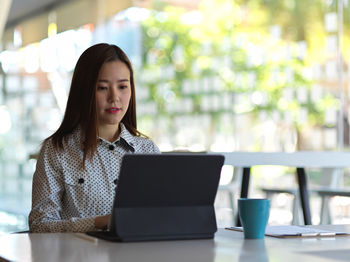 Young woman working on laptop at cafe