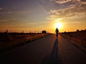 Man standing on road against sky during sunset