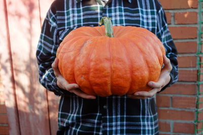 Midsection of man holding pumpkin