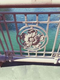 Metal railing by sea against sky