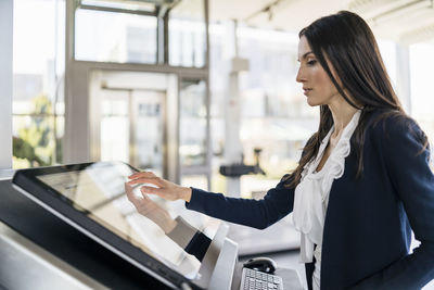 Businesswoman operating machine in a modern factory