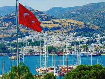 Turkish flag with boats moored in sea by city