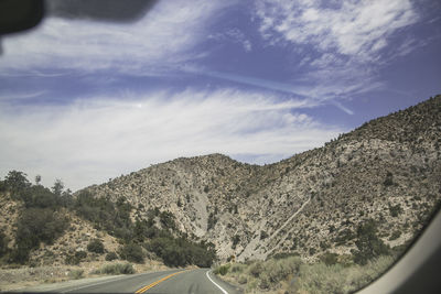 Road by mountains against sky seen through car windshield