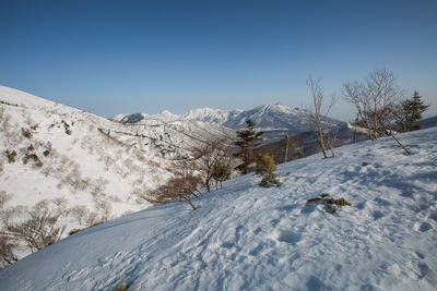 Scenic view of snow covered mountains against clear blue sky