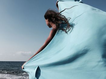 Young woman in sea against sky