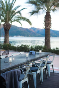 Empty chairs and tables in swimming pool against sea