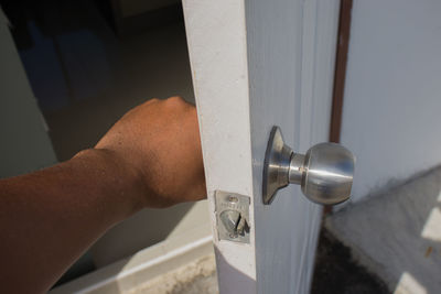 Close-up of hand holding metal door