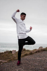 Full length of young man standing in sea against sky