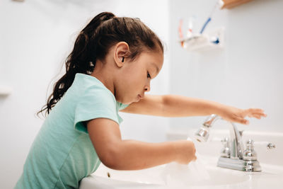 Cute girl washing napkin at sink