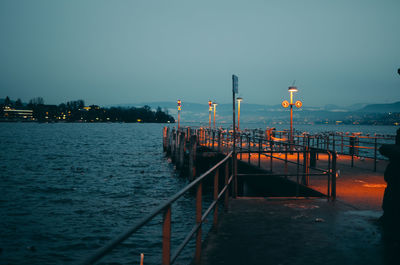 Pier over sea against clear sky at dusk