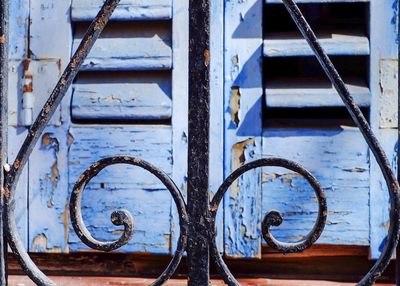 Close-up of metal grate against weathered window