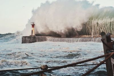 Lighthouse by sea against sky during winter