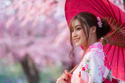 Portrait of smiling woman with pink flower