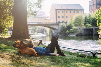 Young man lying down with his dog in park