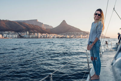 Portrait of young woman standing in sea against clear sky