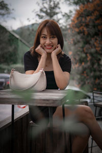 Portrait of young woman sitting on table