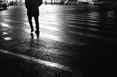 Low section of man walking on wet road