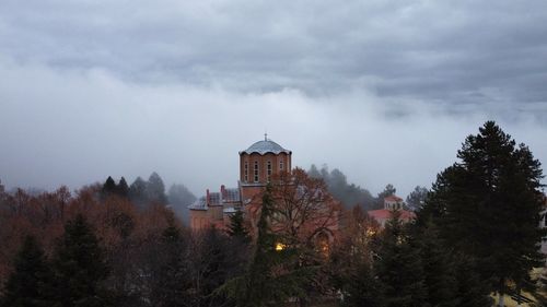 Building by trees against sky during winter