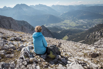 Rear view of woman sitting on top of mountain at watzmann