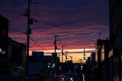 Cars on street in city against sky at sunset