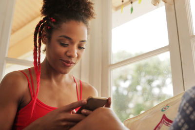 Low angle view of woman using mobile phone while sitting at home