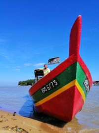 Container ship on beach against blue sky